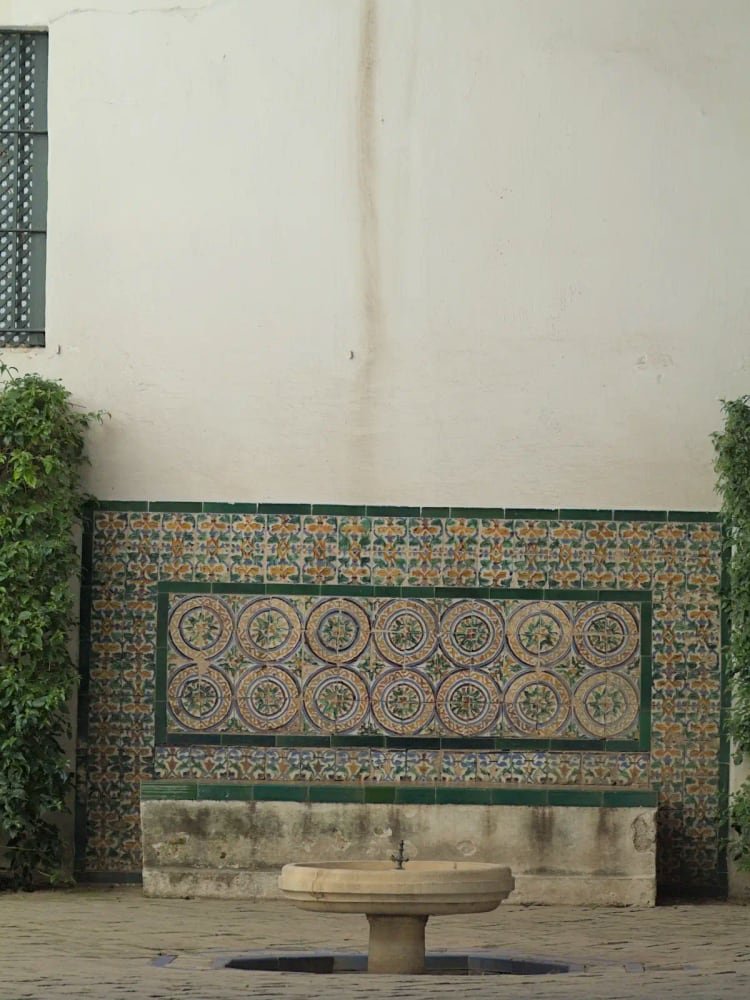 The Patio de las Doncellas at the Real Alcázar de Sevilla — Moorish horseshoe arches, intricate stucco, and a reflecting pool in the Mudéjar style, inscribed UNESCO World Heritage 1987